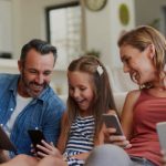 Shot of a happy young family using wireless devices on the sofa at home