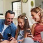 Shot of a happy young family using wireless devices on the sofa at home